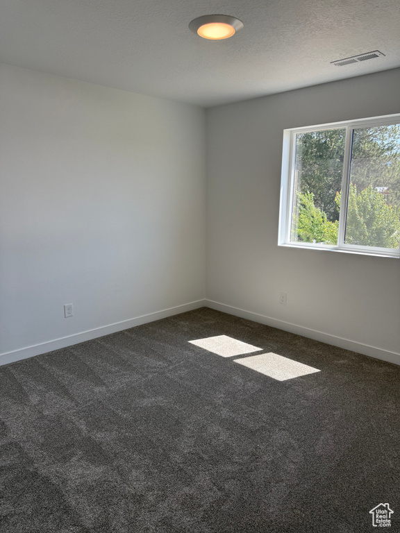 Empty room with dark colored carpet and baseboards