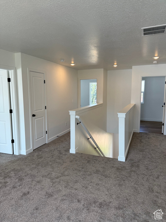 Carpeted empty room featuring a textured ceiling