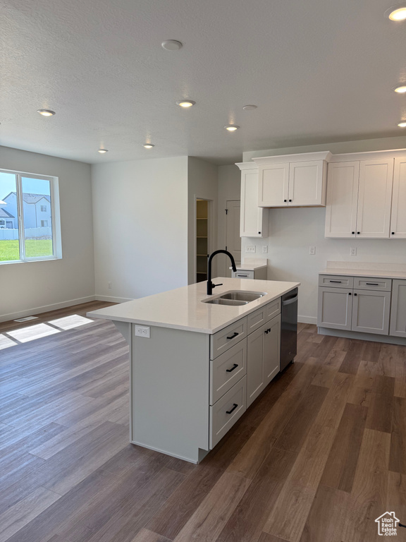 Kitchen with dishwasher, a kitchen island with sink, dark wood-style floors, recessed lighting, and light countertops