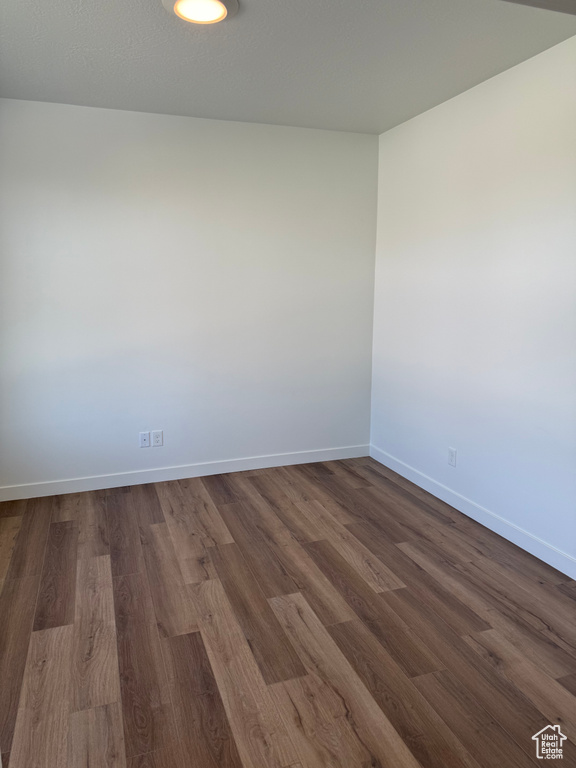 Unfurnished room featuring baseboards and dark wood-style flooring