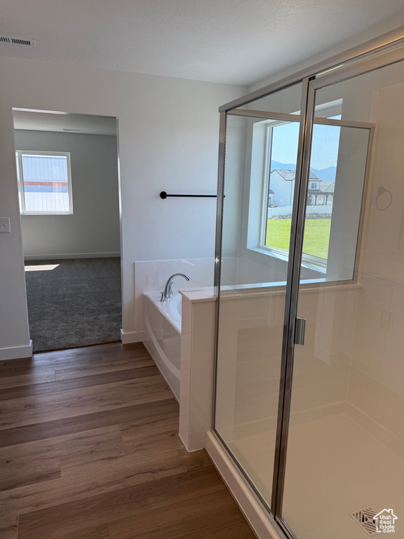 Bathroom with a bath, a shower stall, and wood finished floors
