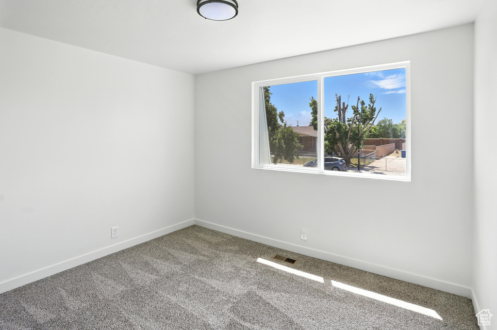 Carpeted spare room featuring baseboards