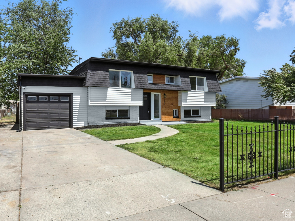 Bi-level home featuring driveway, an attached garage, and brick siding