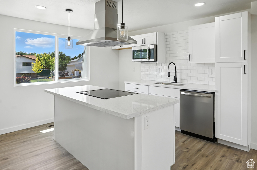 Kitchen featuring stainless steel appliances, island range hood, a kitchen island, tasteful backsplash, and white cabinetry