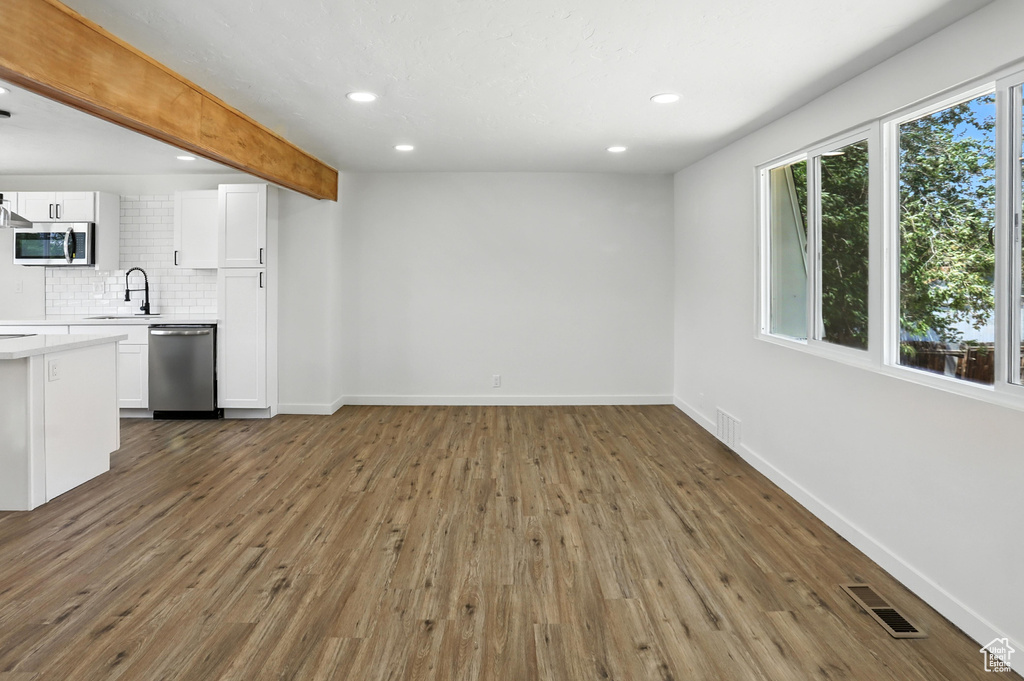 Unfurnished living room featuring wood finished floors, recessed lighting, and beamed ceiling