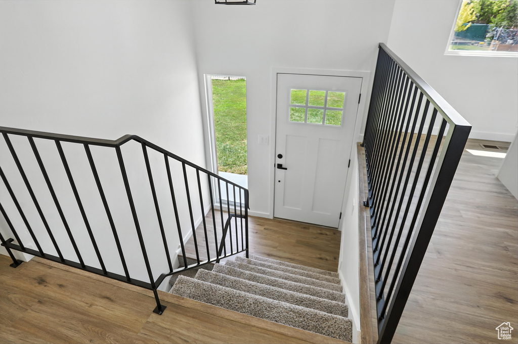 Entryway with wood finished floors, stairs, and a towering ceiling