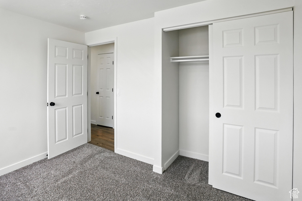 Unfurnished bedroom with dark colored carpet and a closet