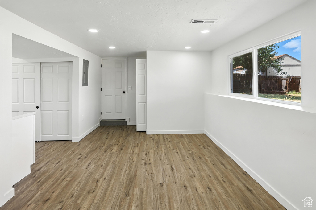 Spare room with wood finished floors, electric panel, and recessed lighting