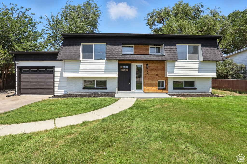 View of front of property featuring an attached garage, concrete driveway, and brick siding