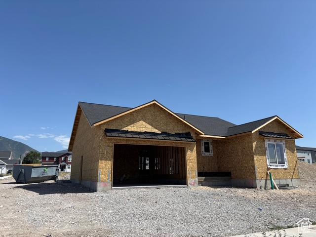 Property under construction featuring an attached garage, driveway, and a standing seam roof