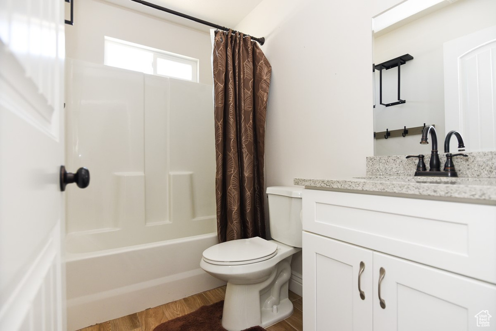 Full bath featuring vanity, shower / bath combo, and wood finished floors