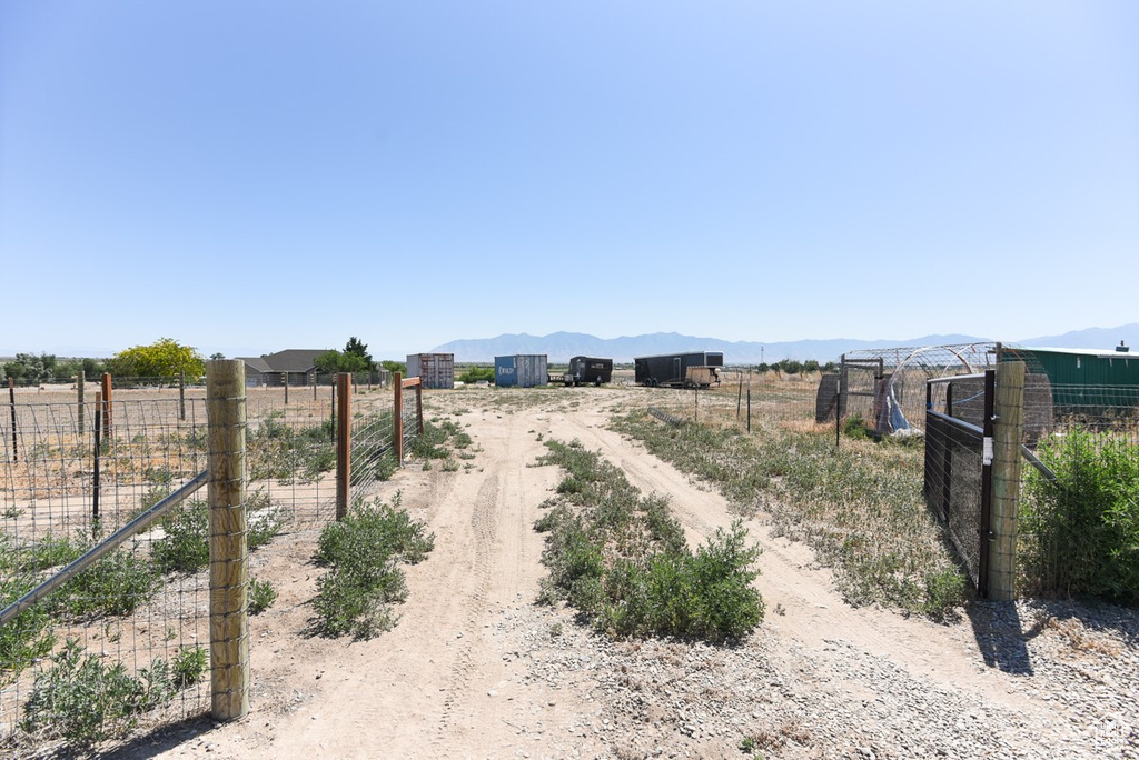 View of dirt / gravel road featuring a view of rural / pastoral area, a mountain view, and a gated entry