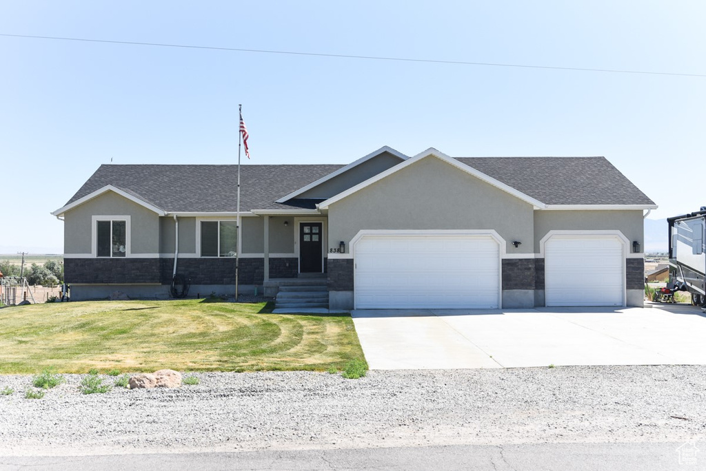Ranch-style house with an attached garage, stucco siding, concrete driveway, a front yard, and a shingled roof
