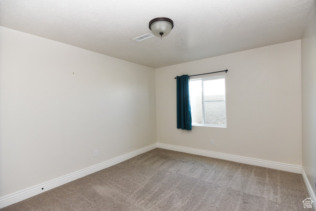 Carpeted empty room featuring baseboards and a textured ceiling