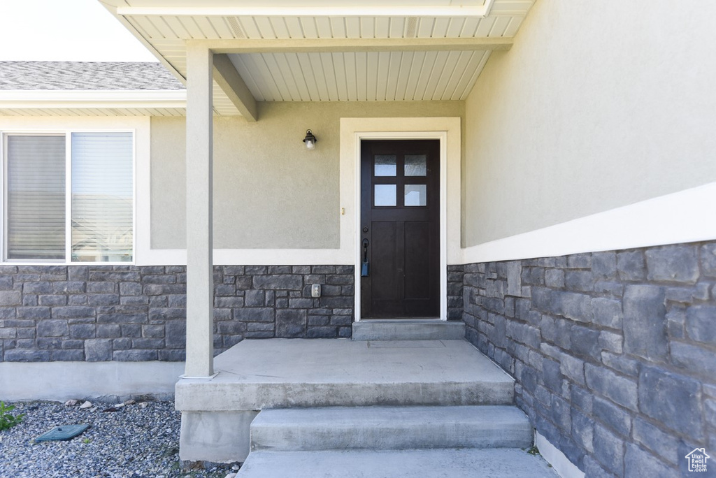 Doorway to property with stone siding and stucco siding