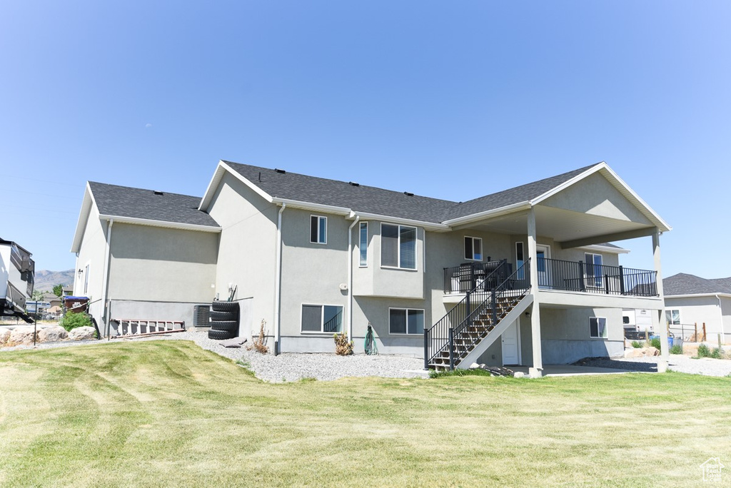 Rear view of property with stairs, a yard, and stucco siding