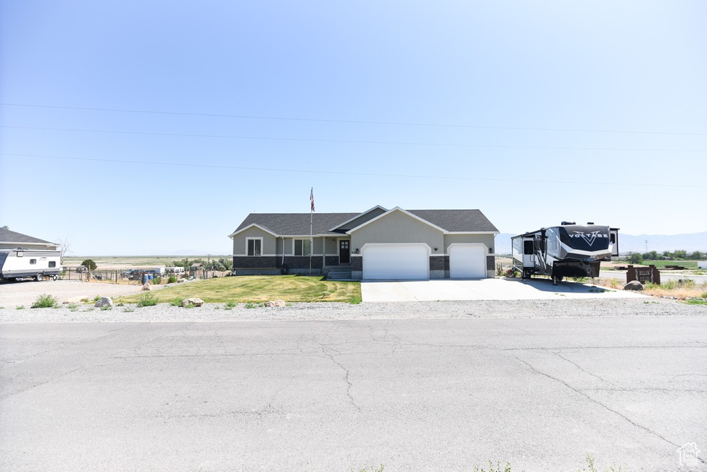Ranch-style house featuring a garage, driveway, stucco siding, and a front lawn