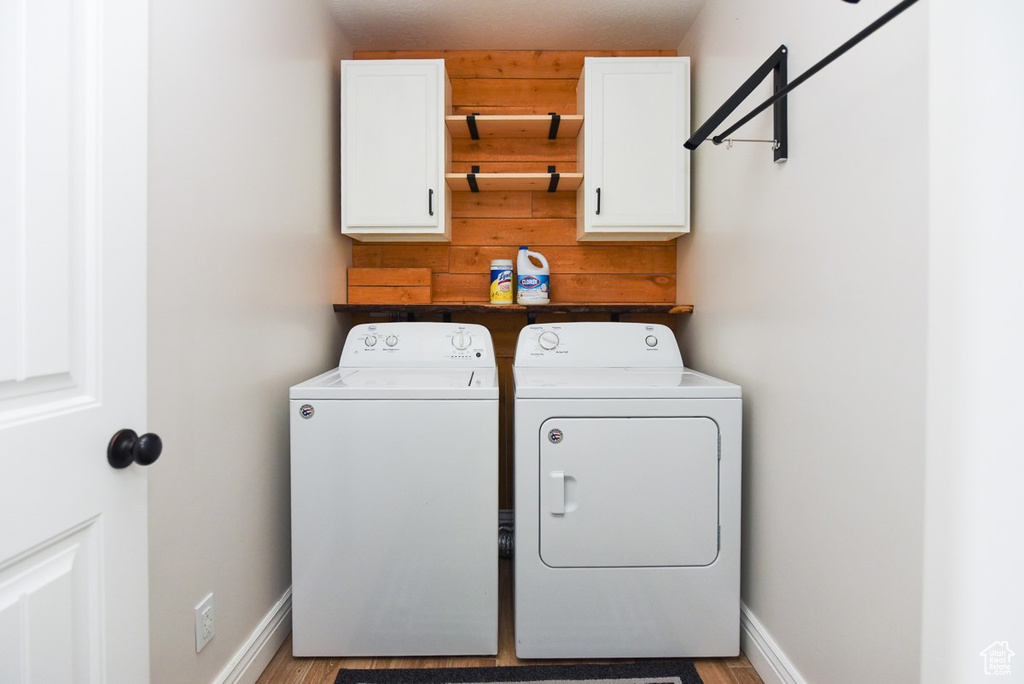 Washroom featuring cabinet space, independent washer and dryer, and light wood-type flooring