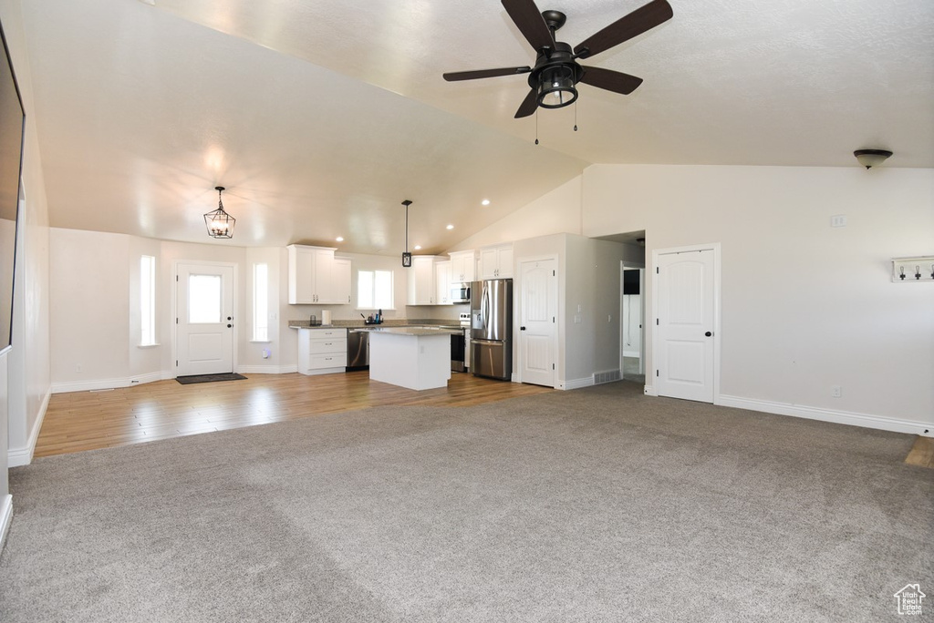 Unfurnished living room with carpet, vaulted ceiling, and ceiling fan