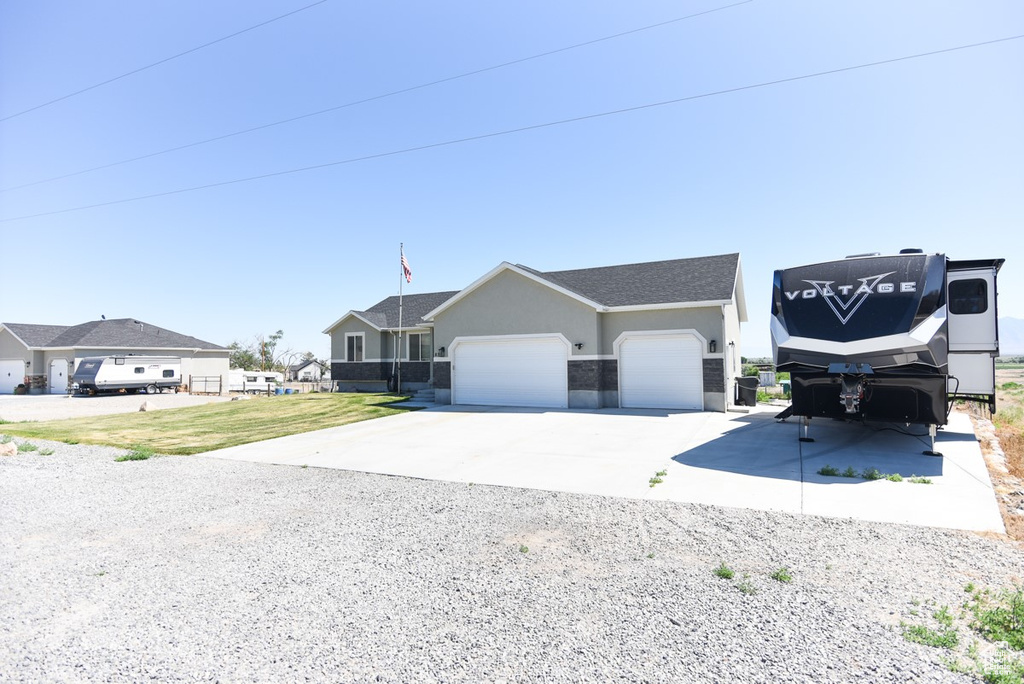 View of front of home with an attached garage, driveway, stucco siding, and a front lawn