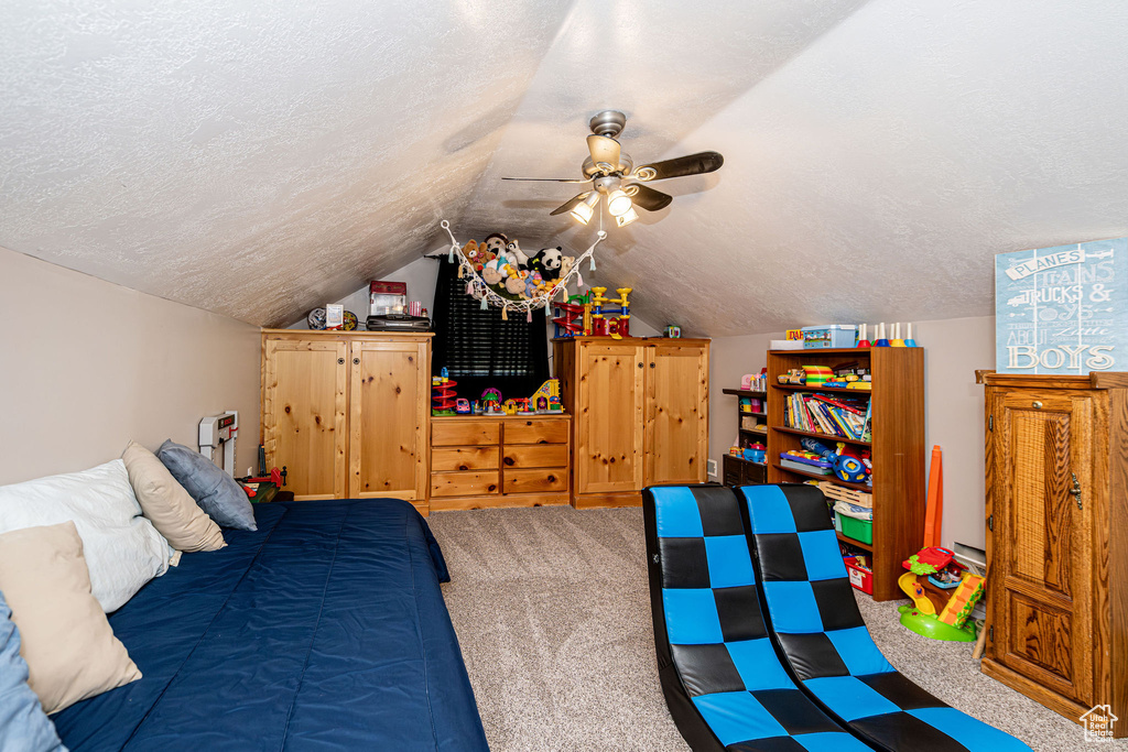 Carpeted bedroom with a textured ceiling, lofted ceiling, and ceiling fan