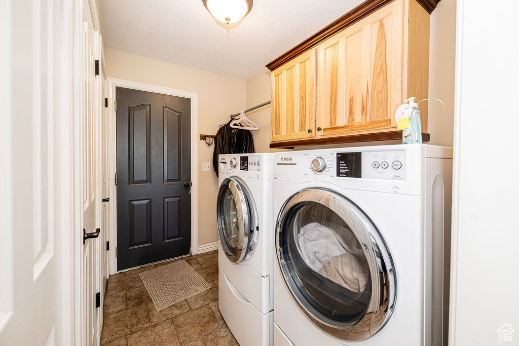 Laundry room featuring washer and clothes dryer, cabinet space, and stone finish floors