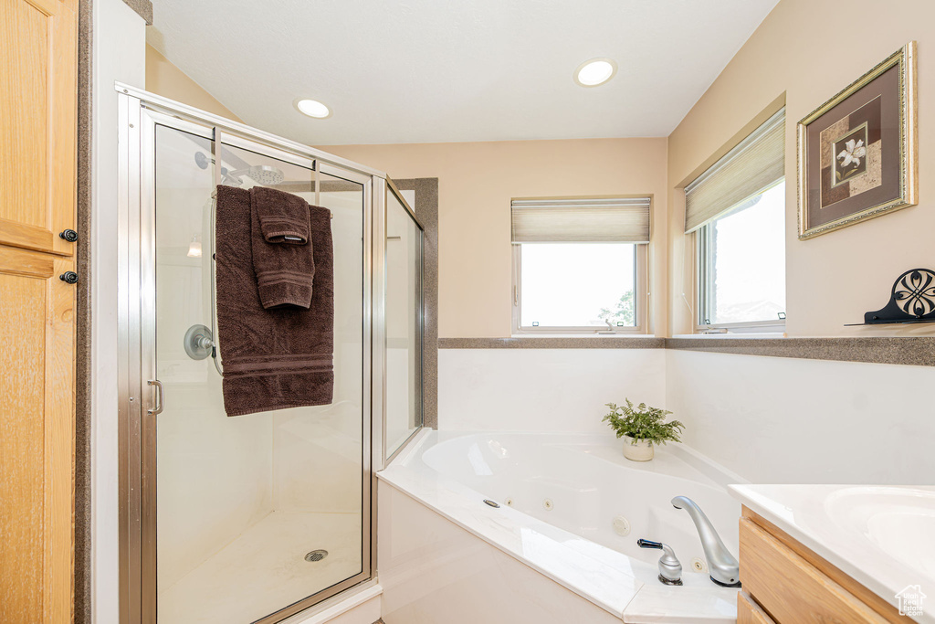 Bathroom featuring a stall shower, a whirlpool tub, vanity, and recessed lighting