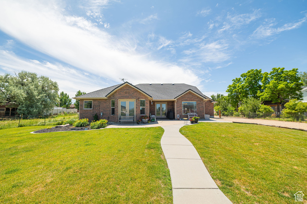 View of front of house featuring french doors, brick siding, a patio, and roof with shingles