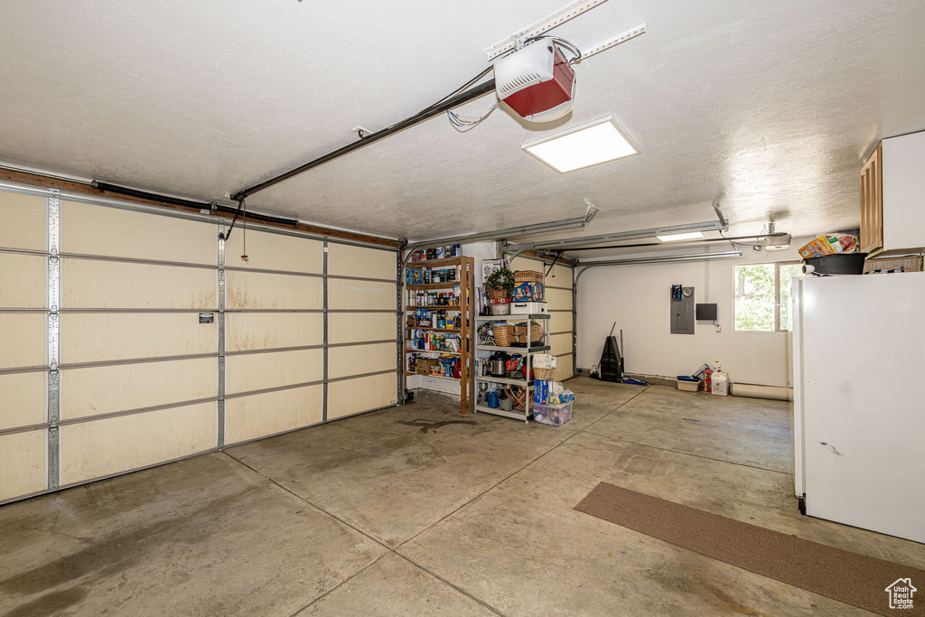 Garage featuring freestanding refrigerator and a garage door opener