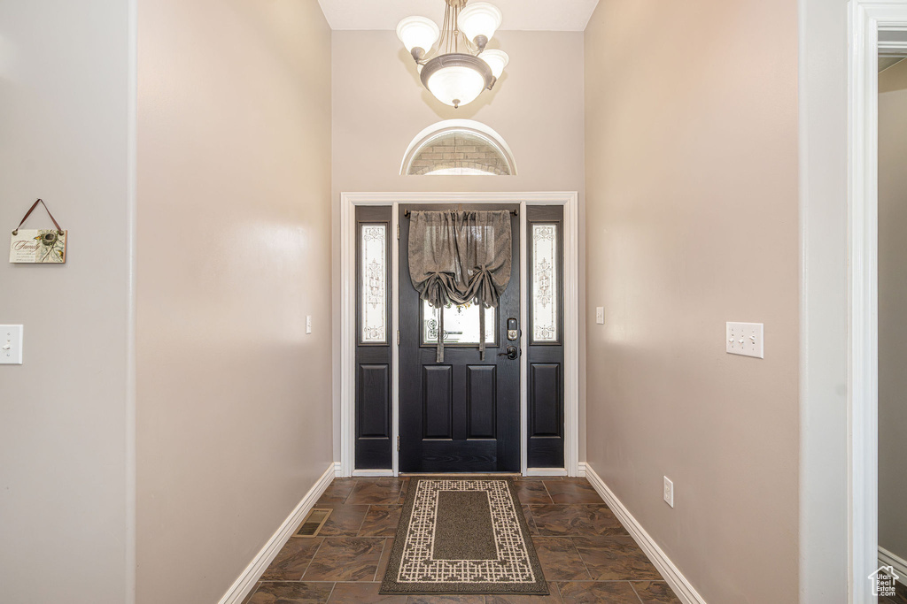 Foyer entrance featuring dark stone finish flooring, a chandelier, and a towering ceiling