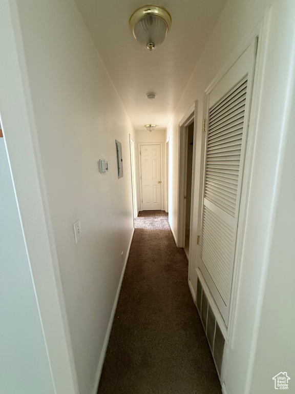 Hallway with dark colored carpet and baseboards