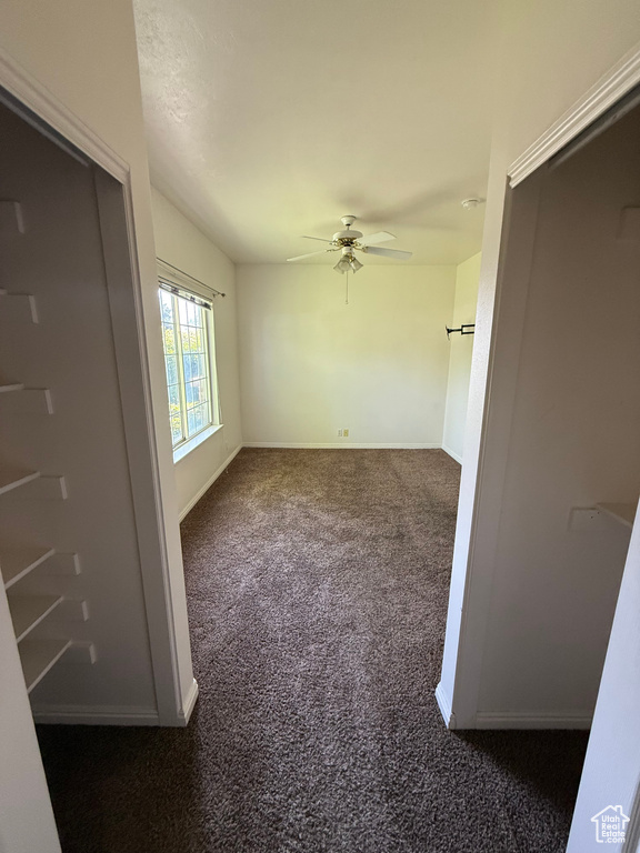 Spare room featuring a ceiling fan and dark carpet
