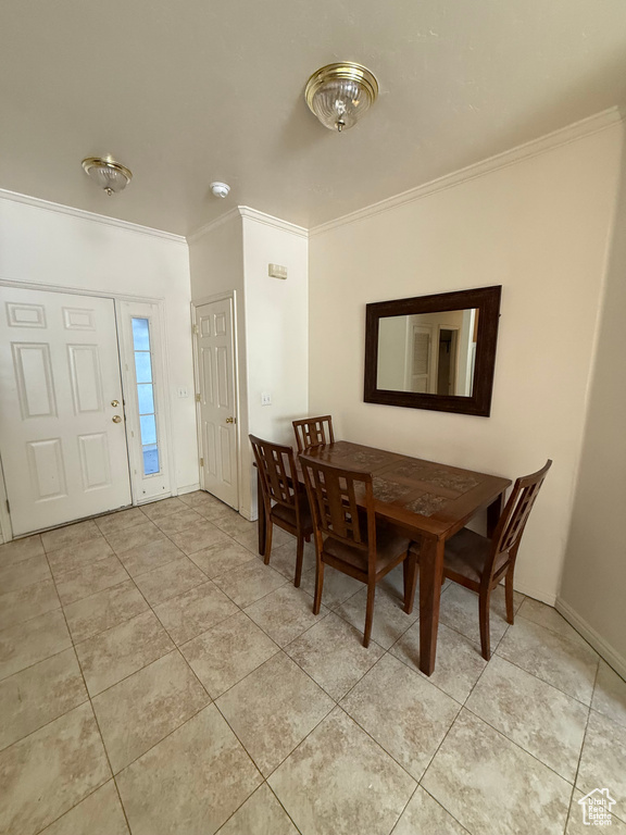 Dining space with crown molding and light tile patterned floors