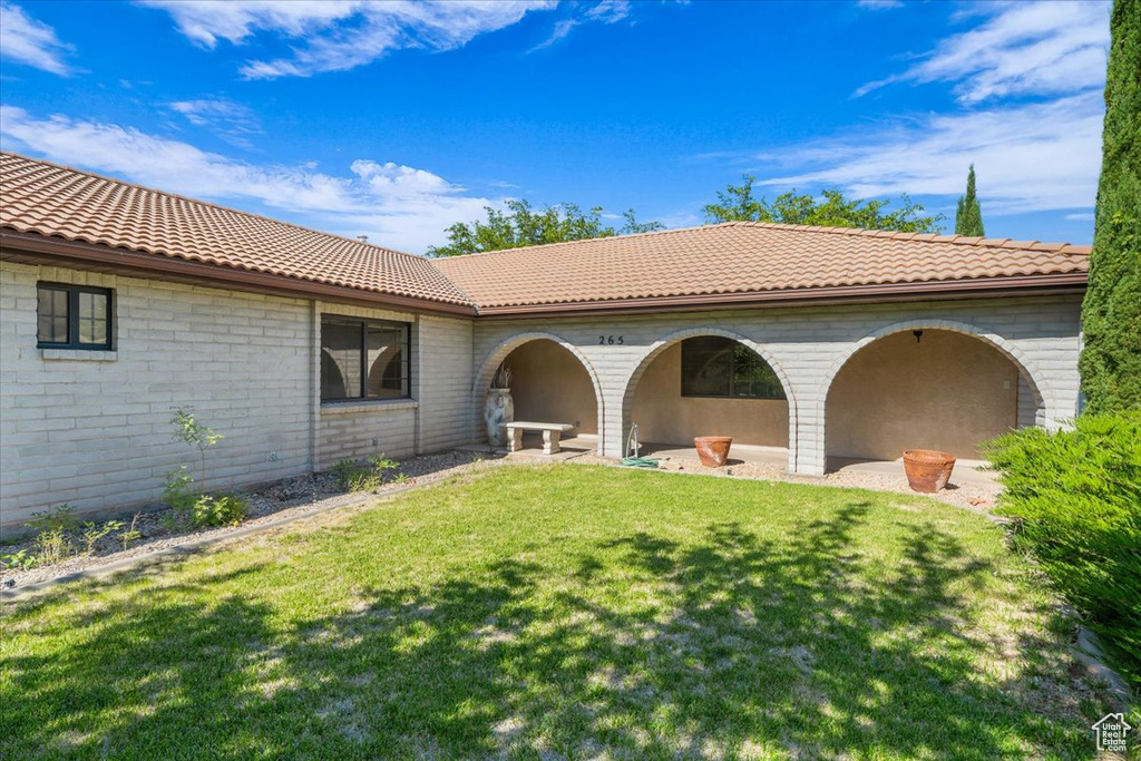 Rear view of property featuring a lawn and a tile roof