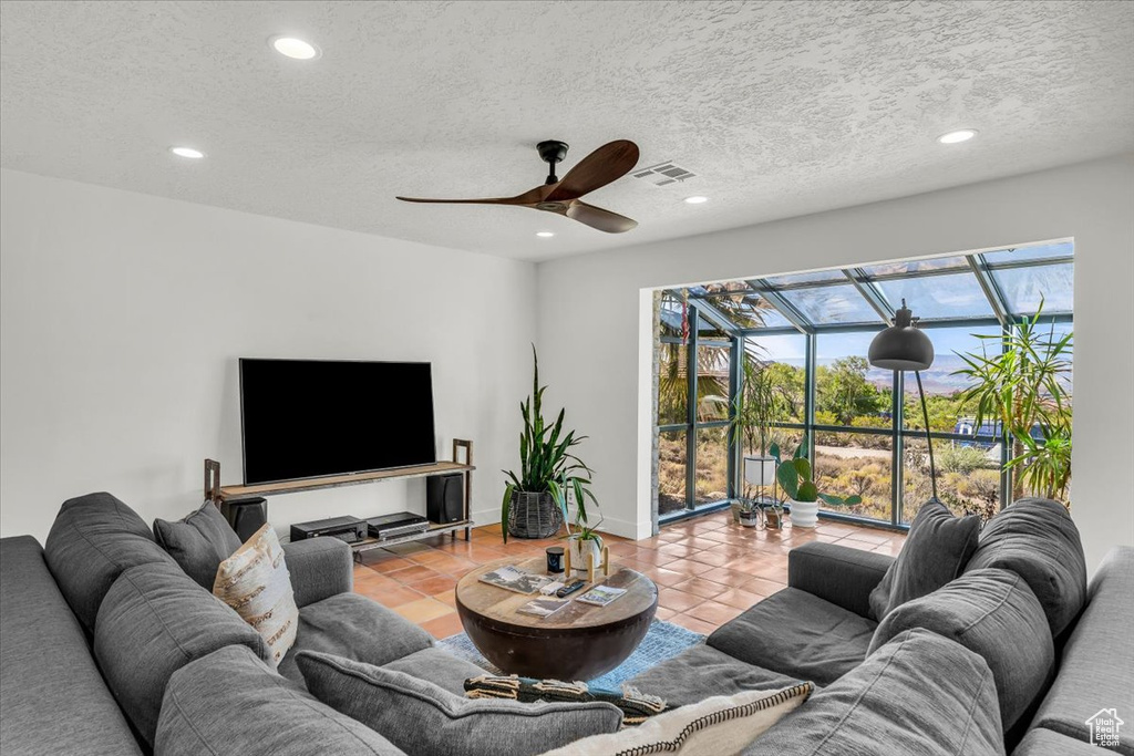 Living area with ceiling fan, recessed lighting, tile patterned flooring, and a textured ceiling