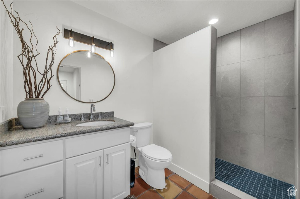 Full bath with vanity, tile patterned flooring, and tiled shower