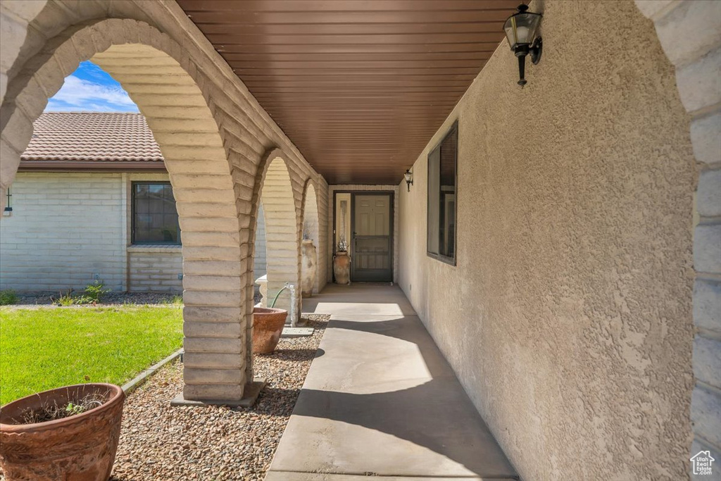 Doorway to property with a tile roof, stucco siding, brick siding, and a lawn