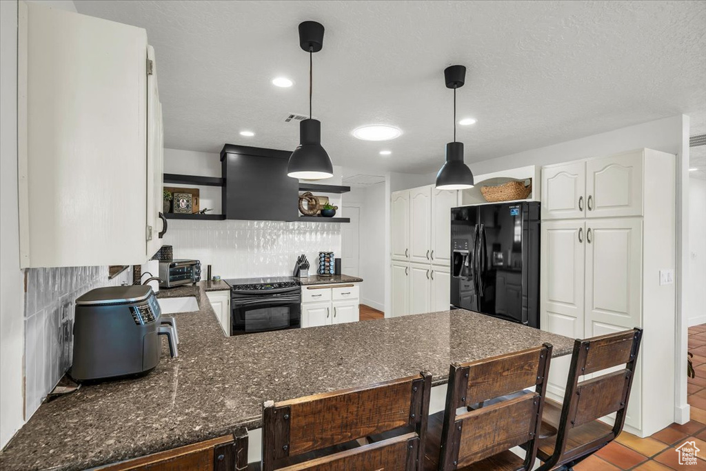 Kitchen featuring black refrigerator with ice dispenser, electric range oven, open shelves, a peninsula, and white cabinets