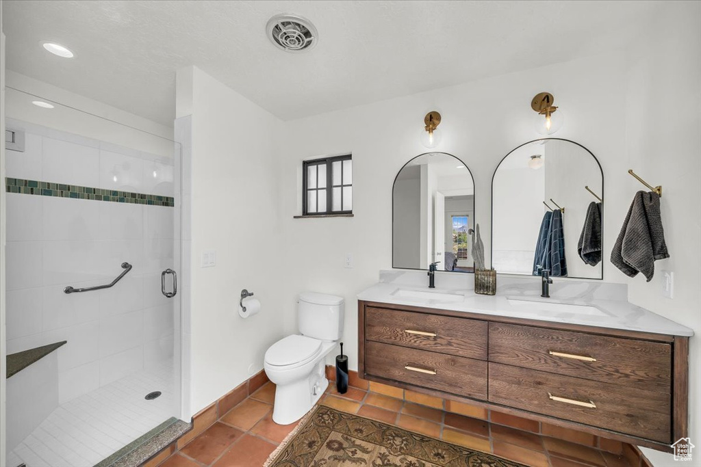 Bathroom with double vanity, a shower stall, and tile patterned floors