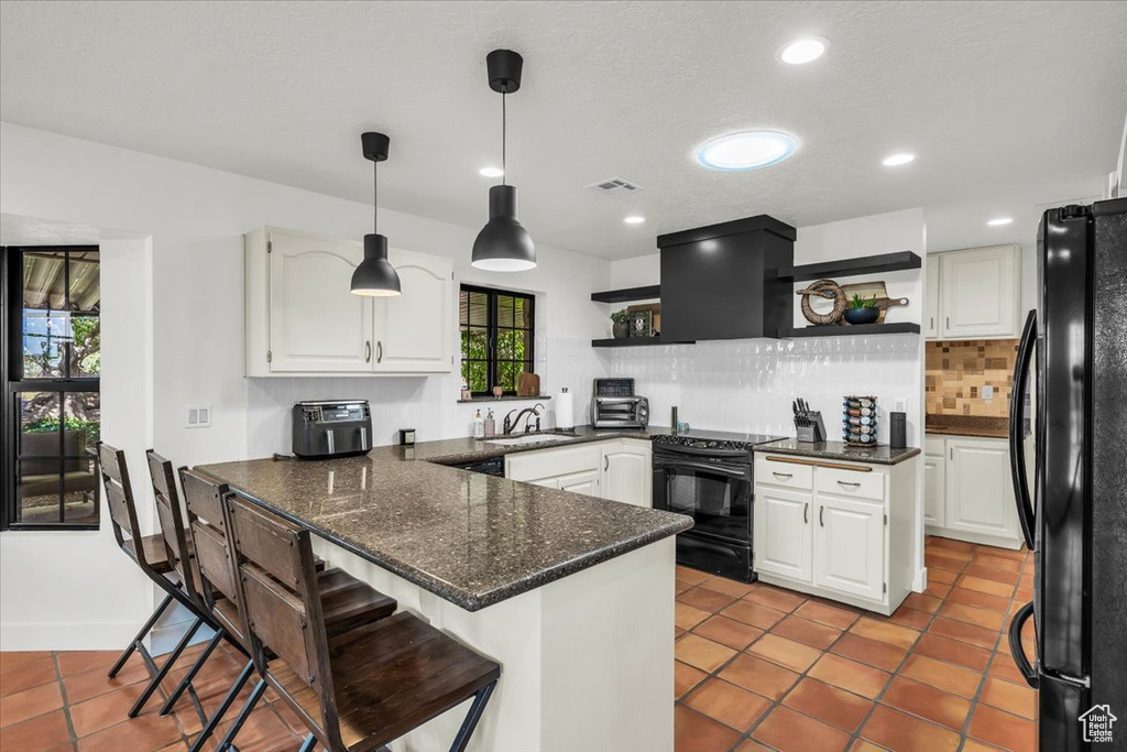 Kitchen featuring black appliances, open shelves, a peninsula, tasteful backsplash, and white cabinets