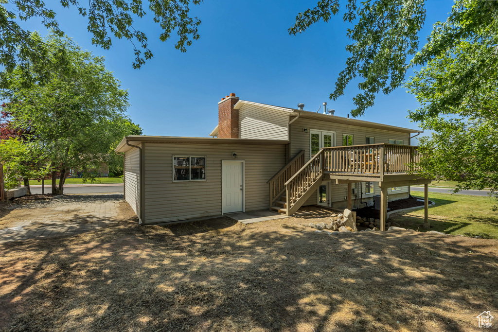 Back of property featuring a deck, stairway, and a chimney