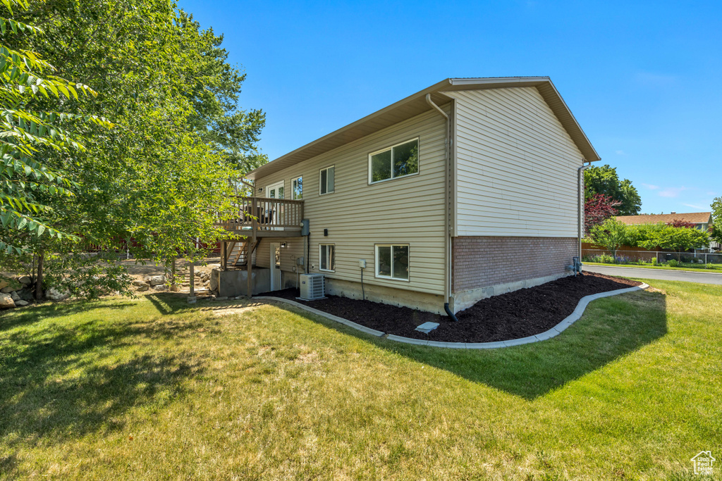 Rear view of property with stairs, a lawn, a wooden deck, and brick siding
