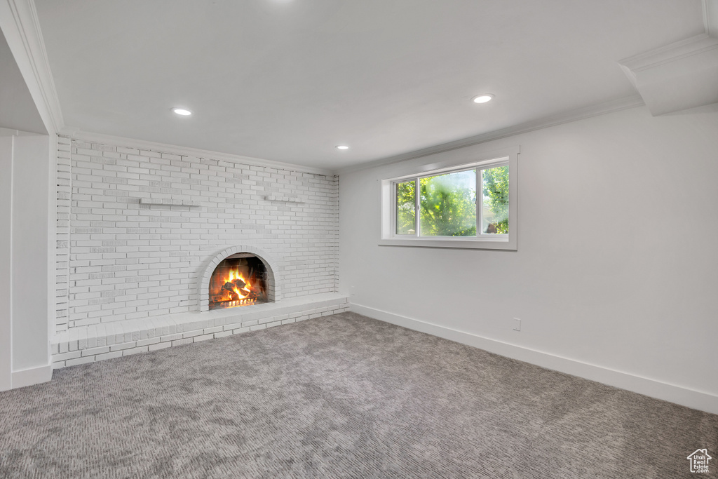 Unfurnished living room with ornamental molding, carpet, recessed lighting, and a fireplace