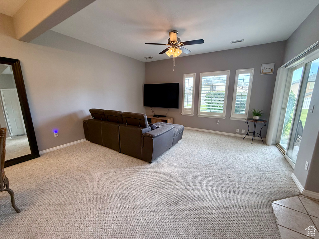 Carpeted living room featuring a ceiling fan and baseboards