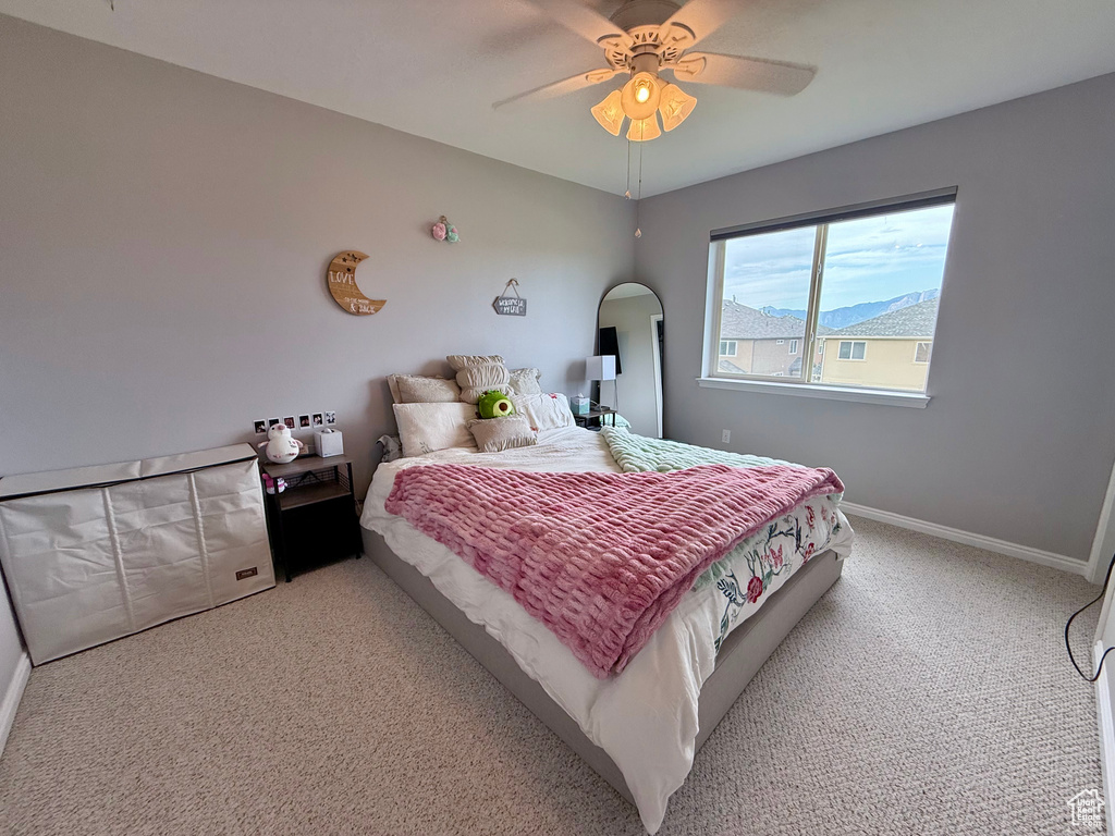 Carpeted bedroom featuring arched walkways and ceiling fan