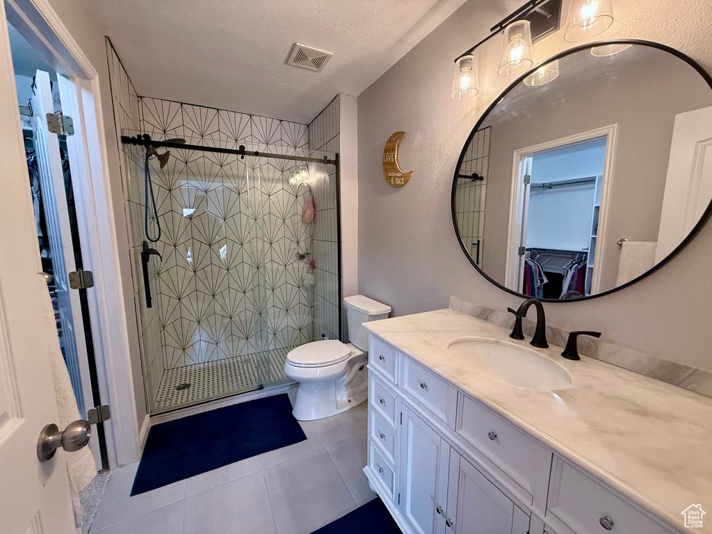 Full bath with vanity, a walk in closet, tile patterned floors, and a stall shower
