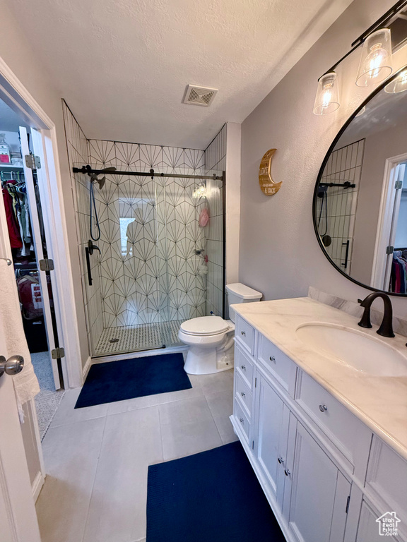 Bathroom with vanity, a stall shower, a spacious closet, a textured ceiling, and tile patterned flooring
