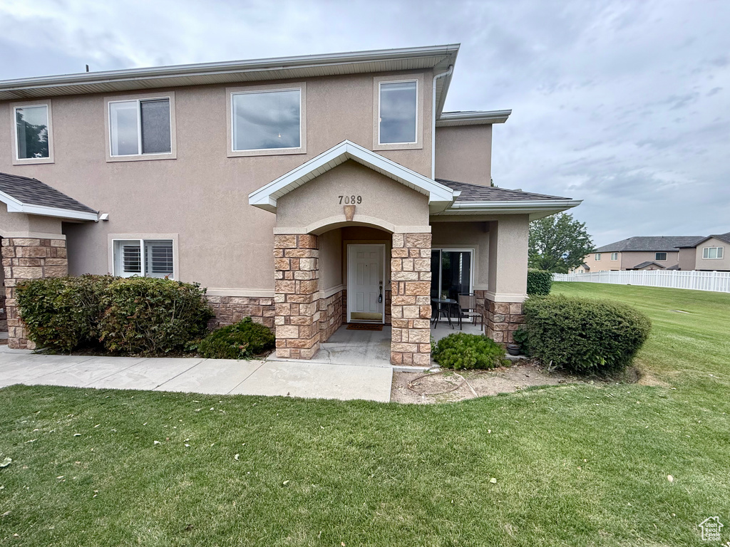 Multi unit property with stone siding, stucco siding, and a front yard