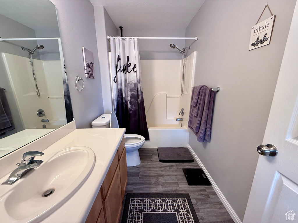 Full bathroom with vanity, shower / bathtub combination with curtain, and wood finished floors