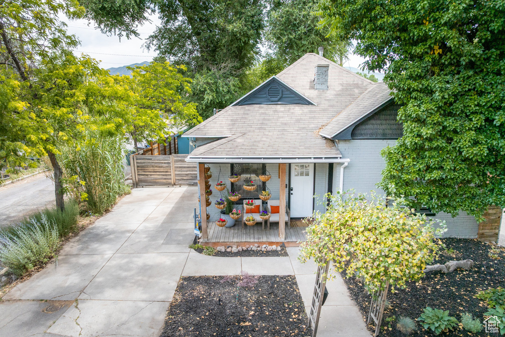 View of front of house with covered porch, roof with shingles, and concrete driveway